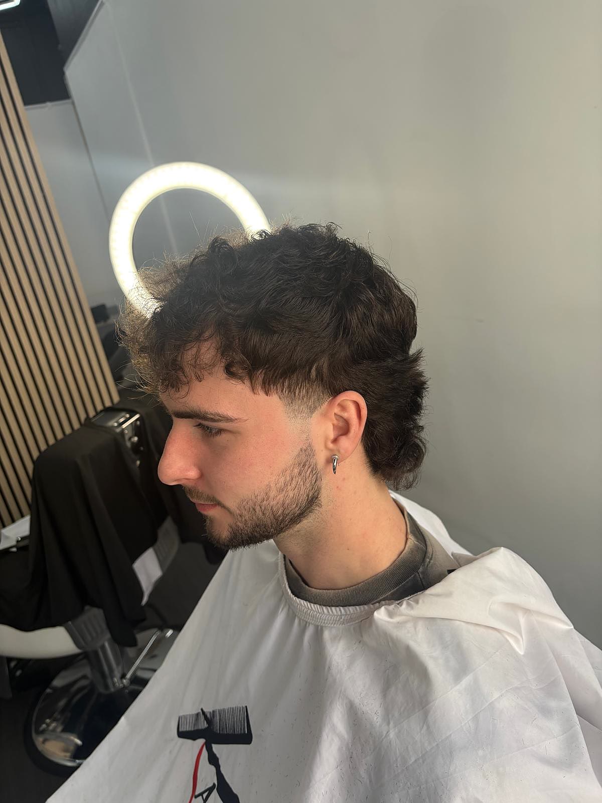 Curly-haired client fresh cut in the chair at Caliber